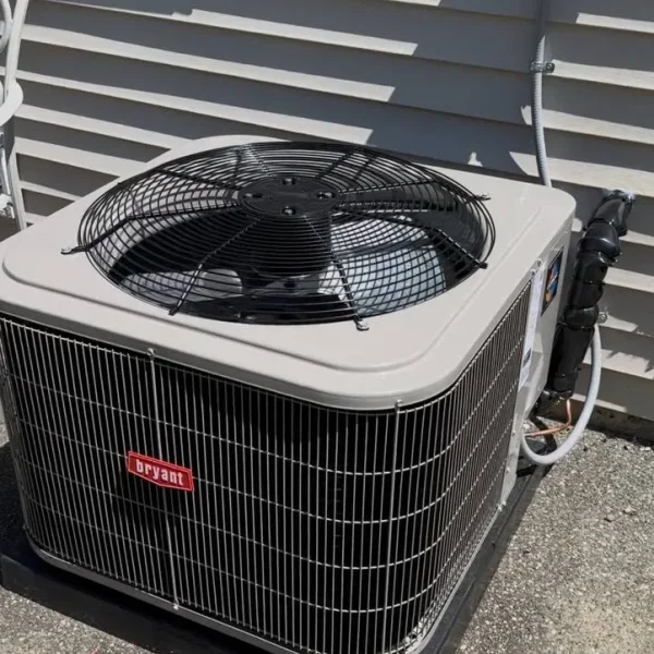 Bryant air conditioner condenser on a pad against grey siding