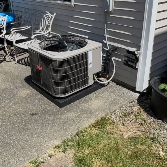 Bryant air conditioner condenser on a pad at the edge of a patio