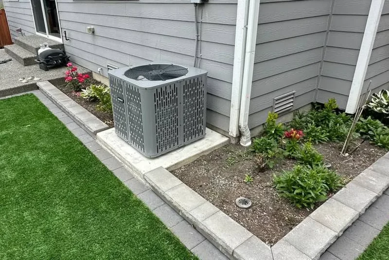Central air conditioner installed beside a garden bed and lawn