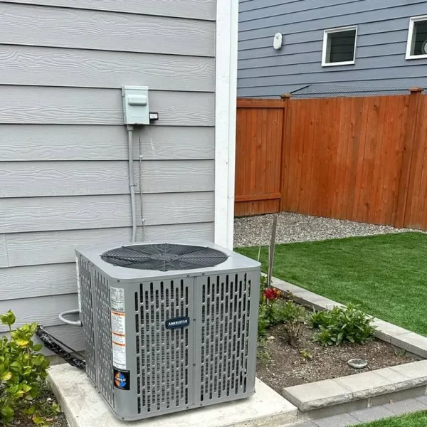 Central air conditioner installed on a concrete pad beside a lawn