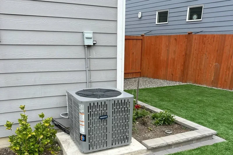 Central air conditioner installed on a concrete pad beside a lawn
