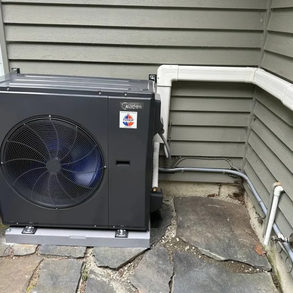 Midea heat pump installed on a flagstone patio with a lineset cover