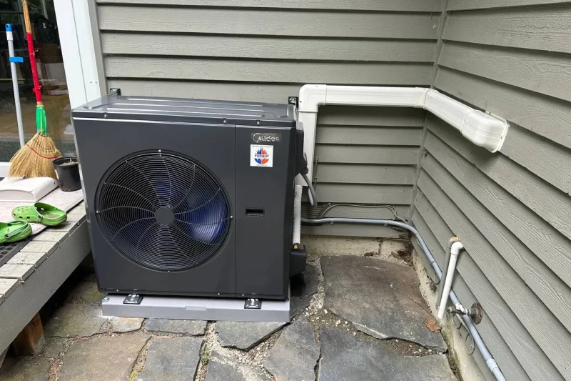 Midea heat pump installed on a flagstone patio with a lineset cover