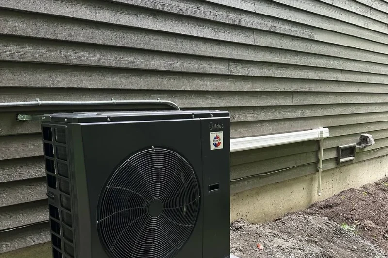 Midea heat pump outdoor unit, front view, installed beside a home