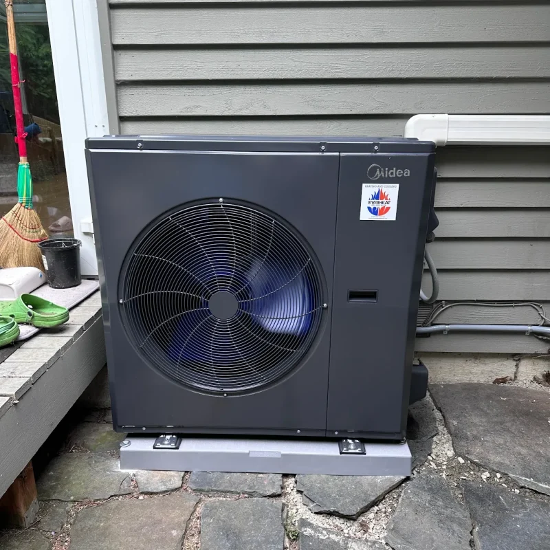 Midea outdoor unit with a dark case standing on flagstone