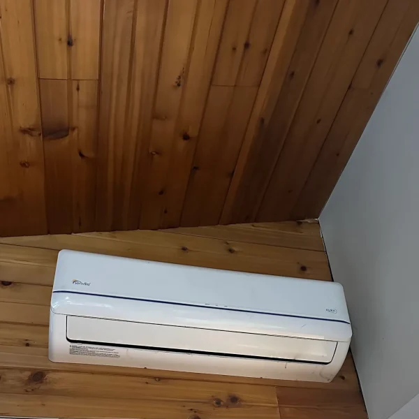 Mini-split indoor head mounted on a wall under a cedar ceiling