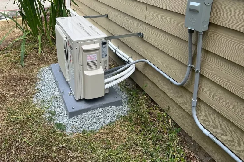 Mini-split outdoor unit with disconnect box and conduit run along the wall