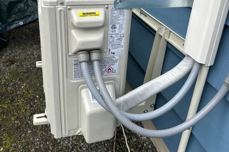 Mini-split outdoor unit mounted on a wall bracket with insulated lineset