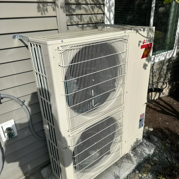 Outdoor unit lifted onto a wall bracket above the ground