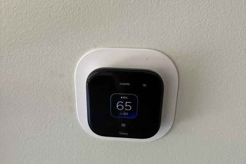 Smart thermostat installed on a wall and set to 65 degrees