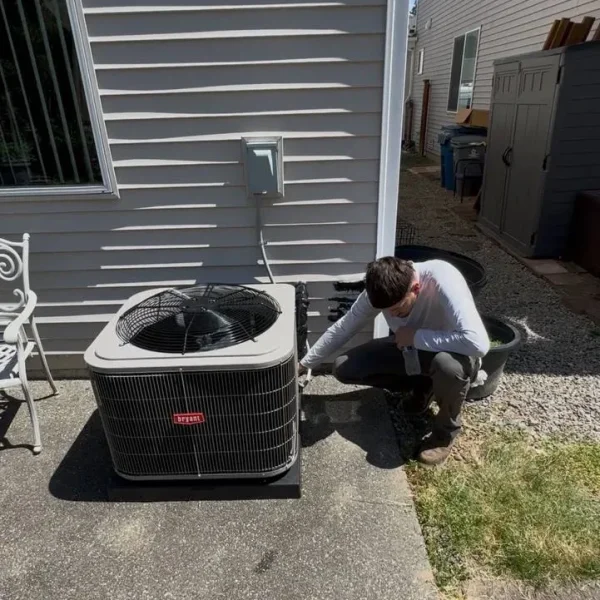 Technician crouching beside an outdoor condenser during the install